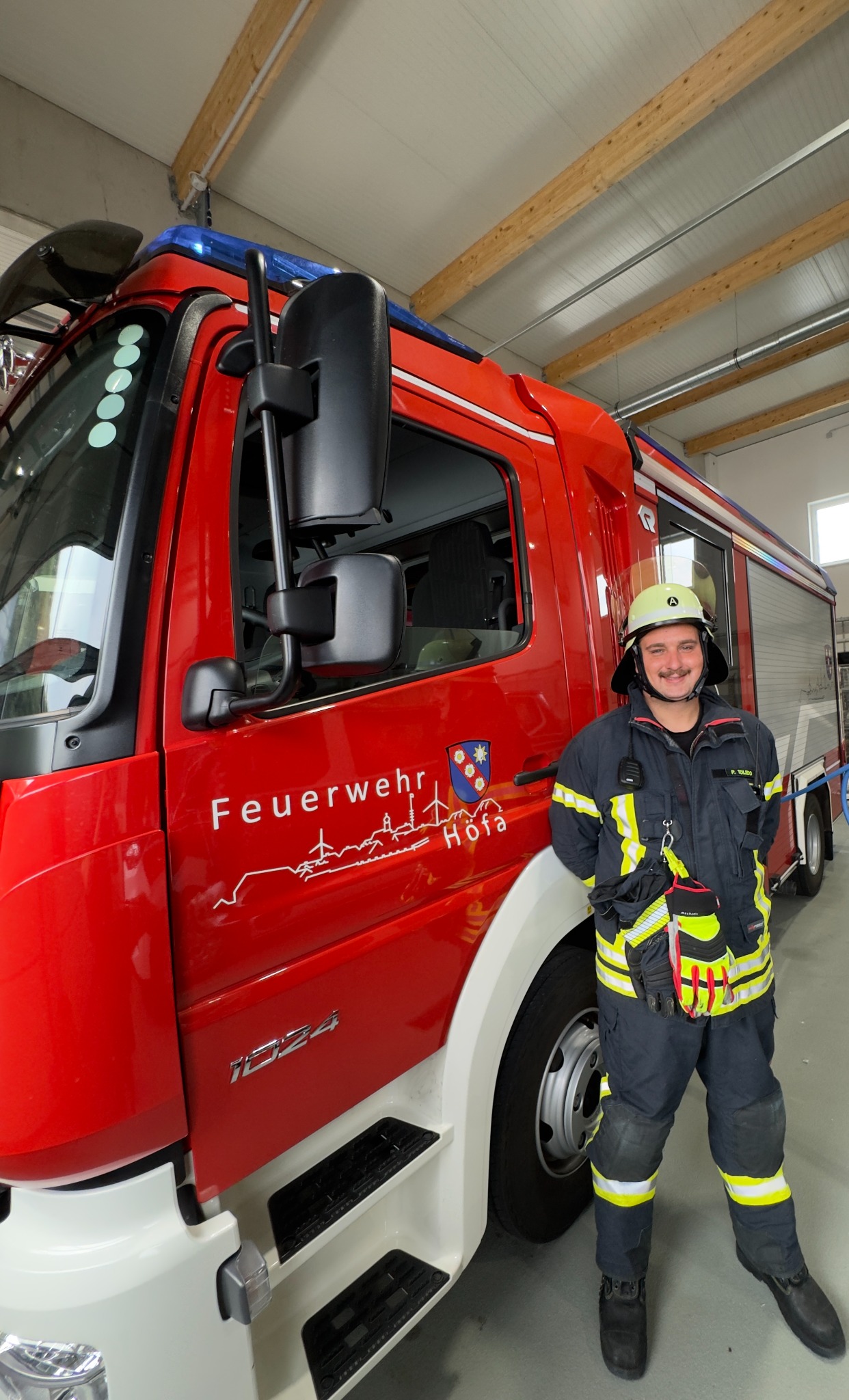 Patrick in firefighting gear beside a Höfa fire brigade vehicle.